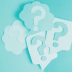 Multiple paper cut‑outs of question marks arranged on a light blue background.