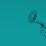 Hand holding a megaphone against a solid teal background, symbolizing communication or announcement.