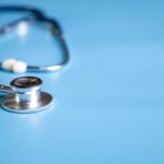 A stethoscope lying on a light blue surface.