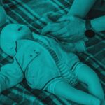 Hands performing CPR compressions on an infant training manikin.