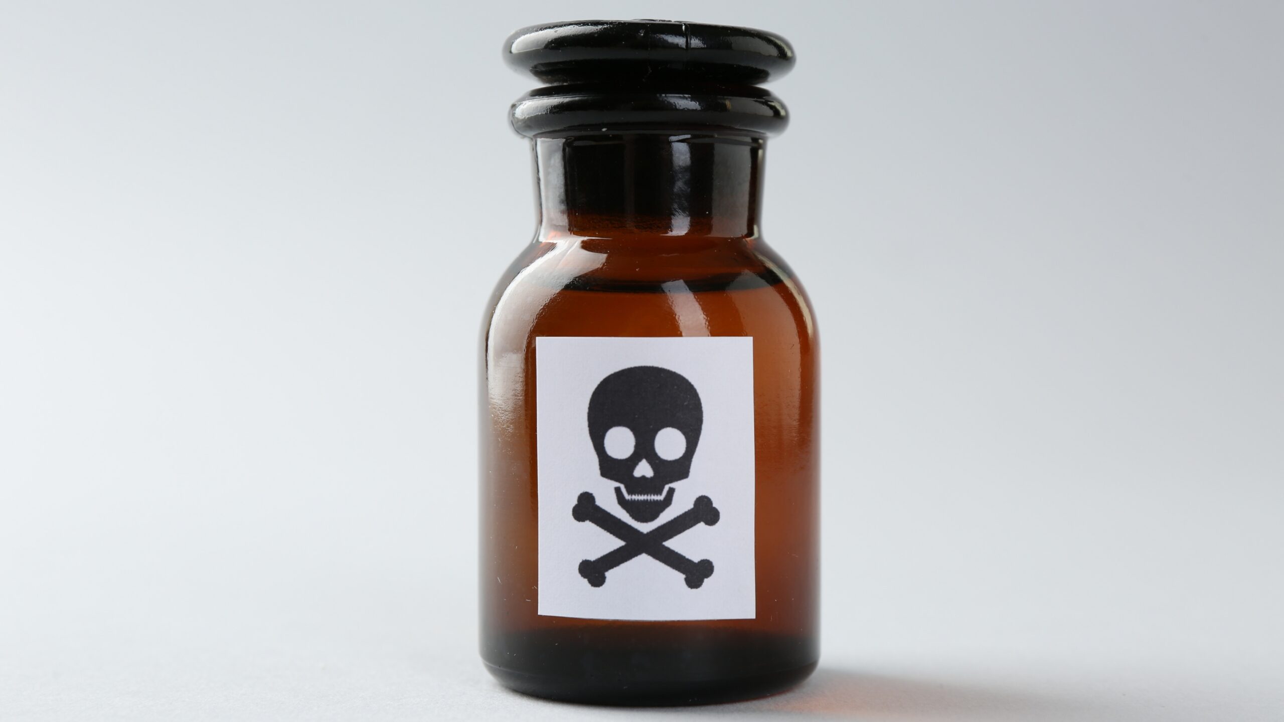 Brown glass bottle with a skull and crossbones warning label, symbolizing poison or toxic substances.