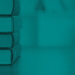 Stack of hardcover books on a table with a blurred bookshelf background.