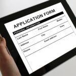 Person holding a tablet displaying an online application form.